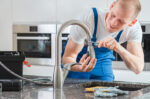 smiling man repairing faucet